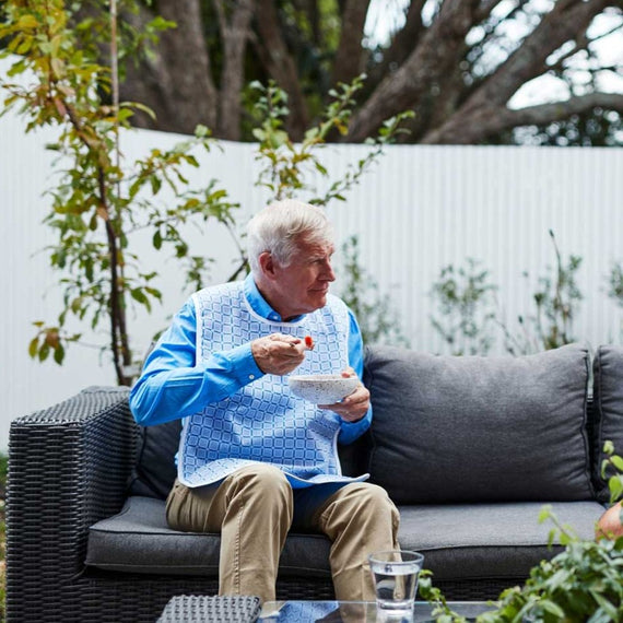 Elderly man wearing blue square pattern eating outdoor